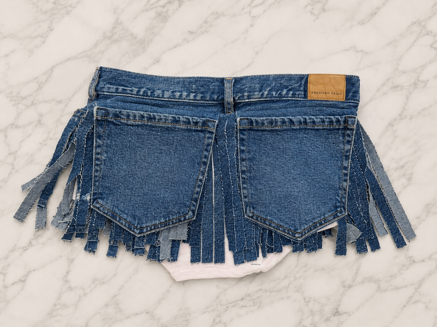 Mini denim fringe skirt with large back pockets
